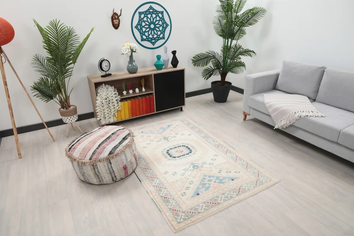 Overhead angle of the rug in a living room, highlighting its ivory, rose, and blue tones and geometric design.