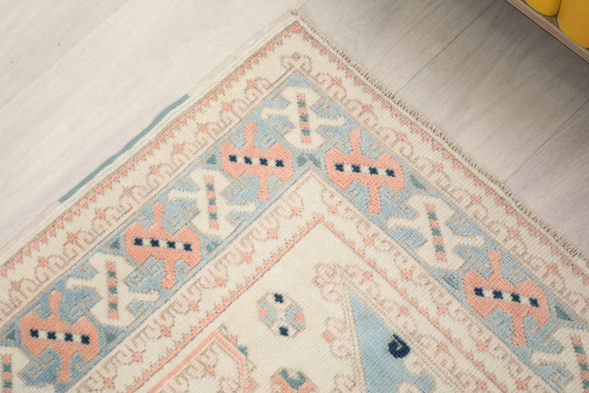 Top left corner of the rug, detailing the border patterns and the subtle color variations.