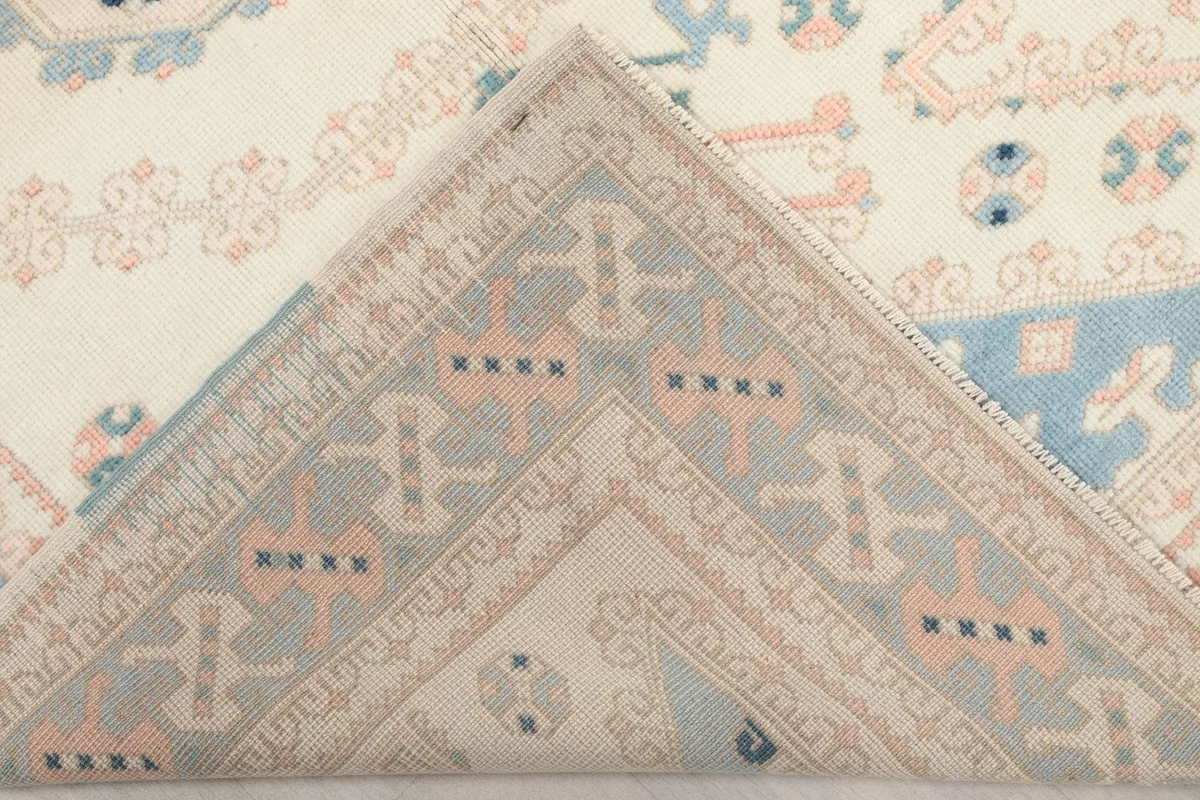 Corner of the rug folded back to reveal the cotton foundation and the reverse side of the hand-knotted wool pile.