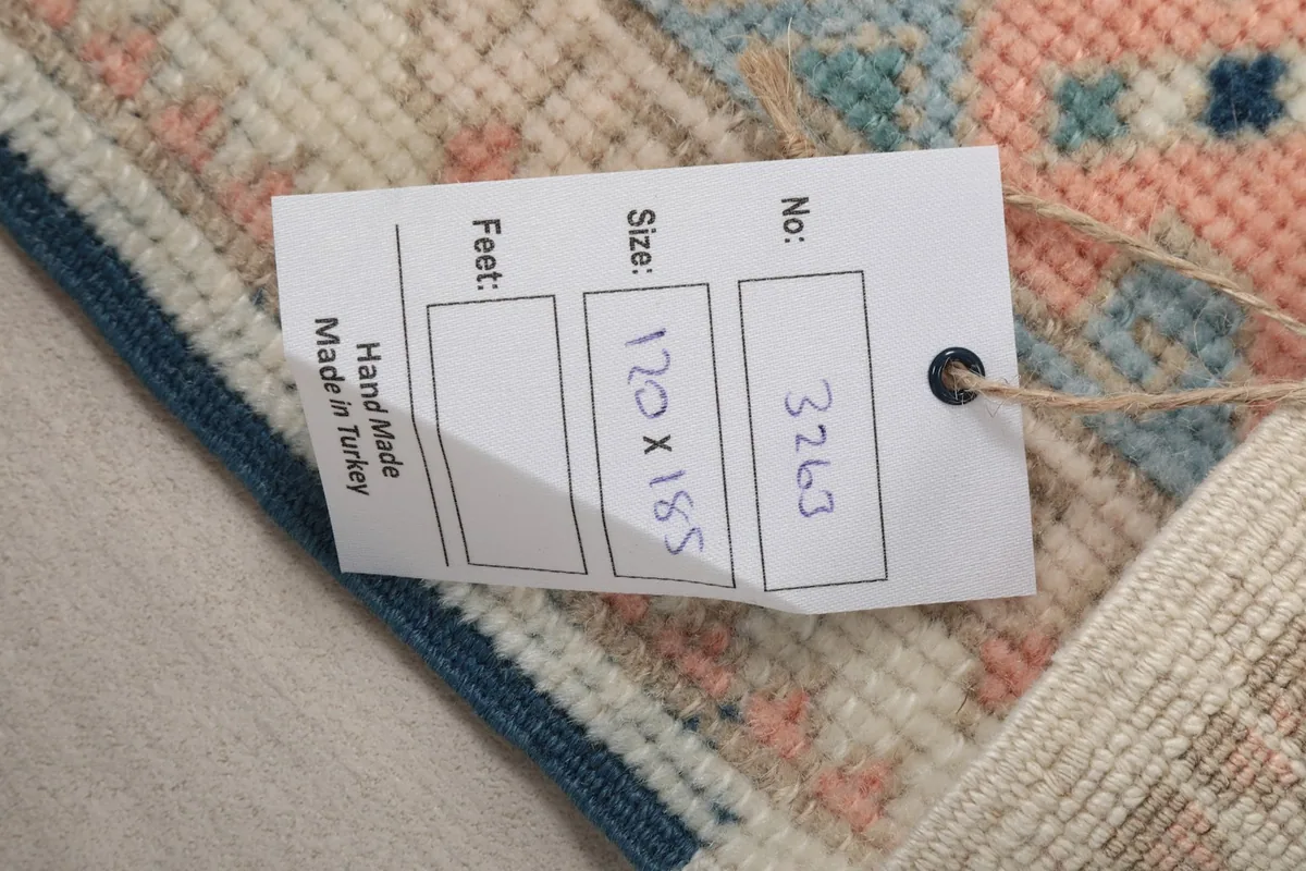 Product tag attached to the rug, displaying its size in centimeters and the 'Hand Made in Turkey' label.