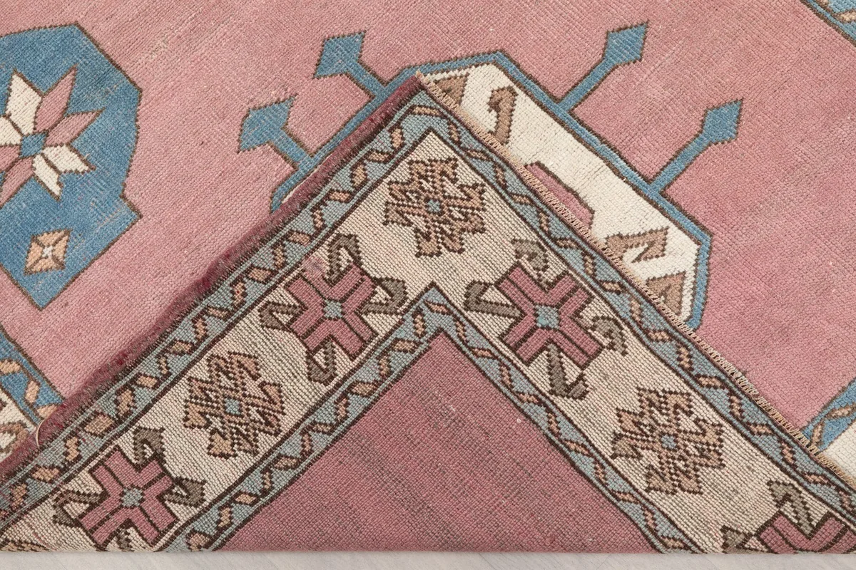 Folded corner of the rug, showing the reverse side and cotton foundation