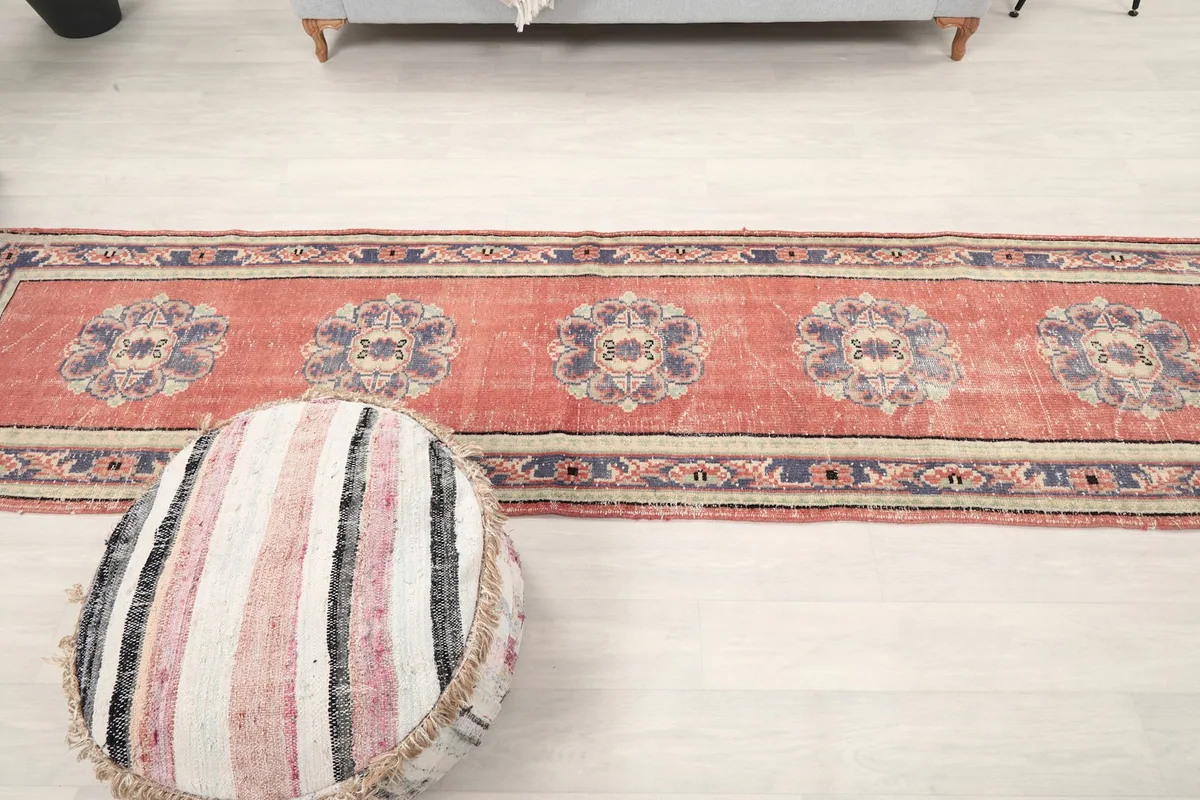 Long view of the vintage runner rug stretching across a room, showcasing its full length and pattern repeat