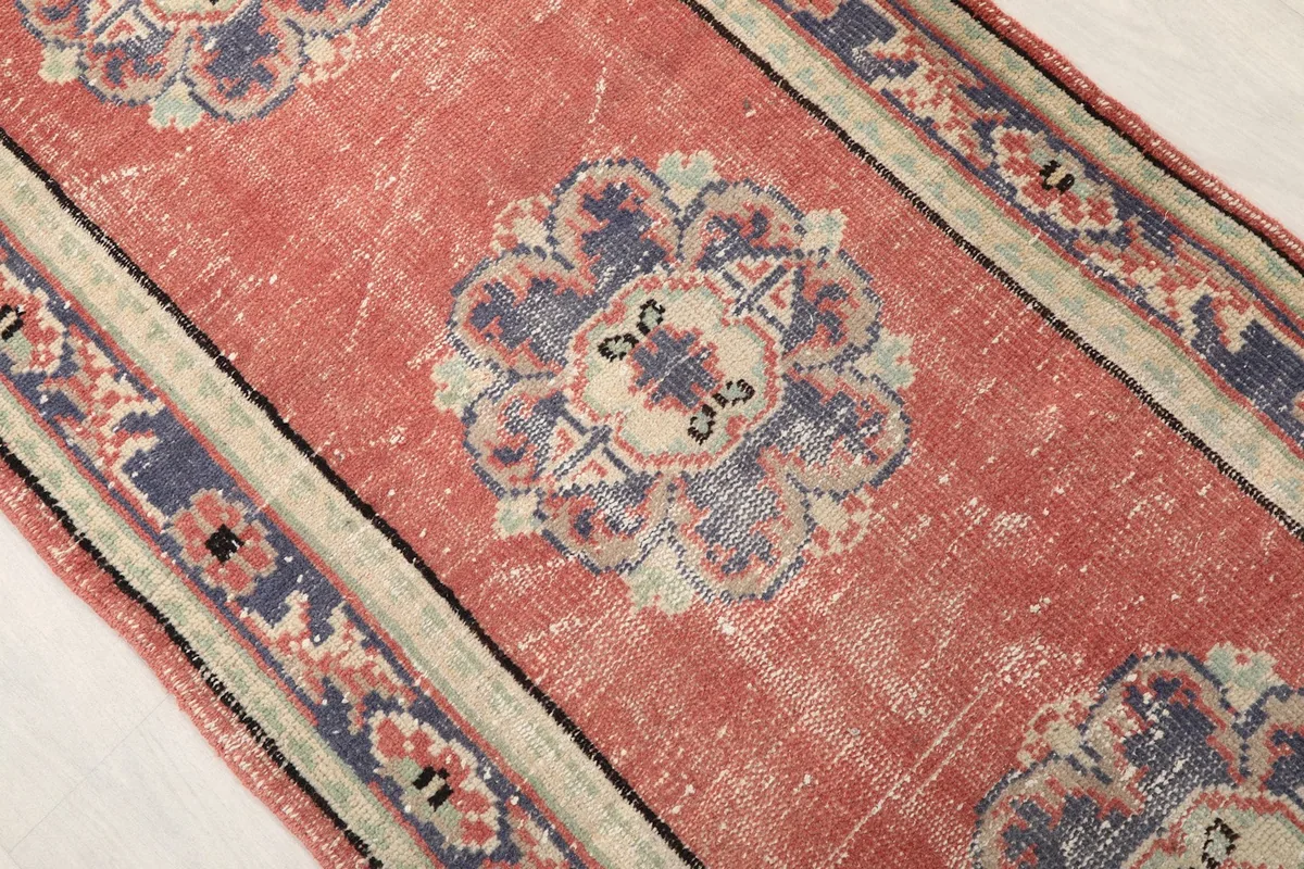 Close-up of a central navy medallion motif on the rose field, showing texture and color variations