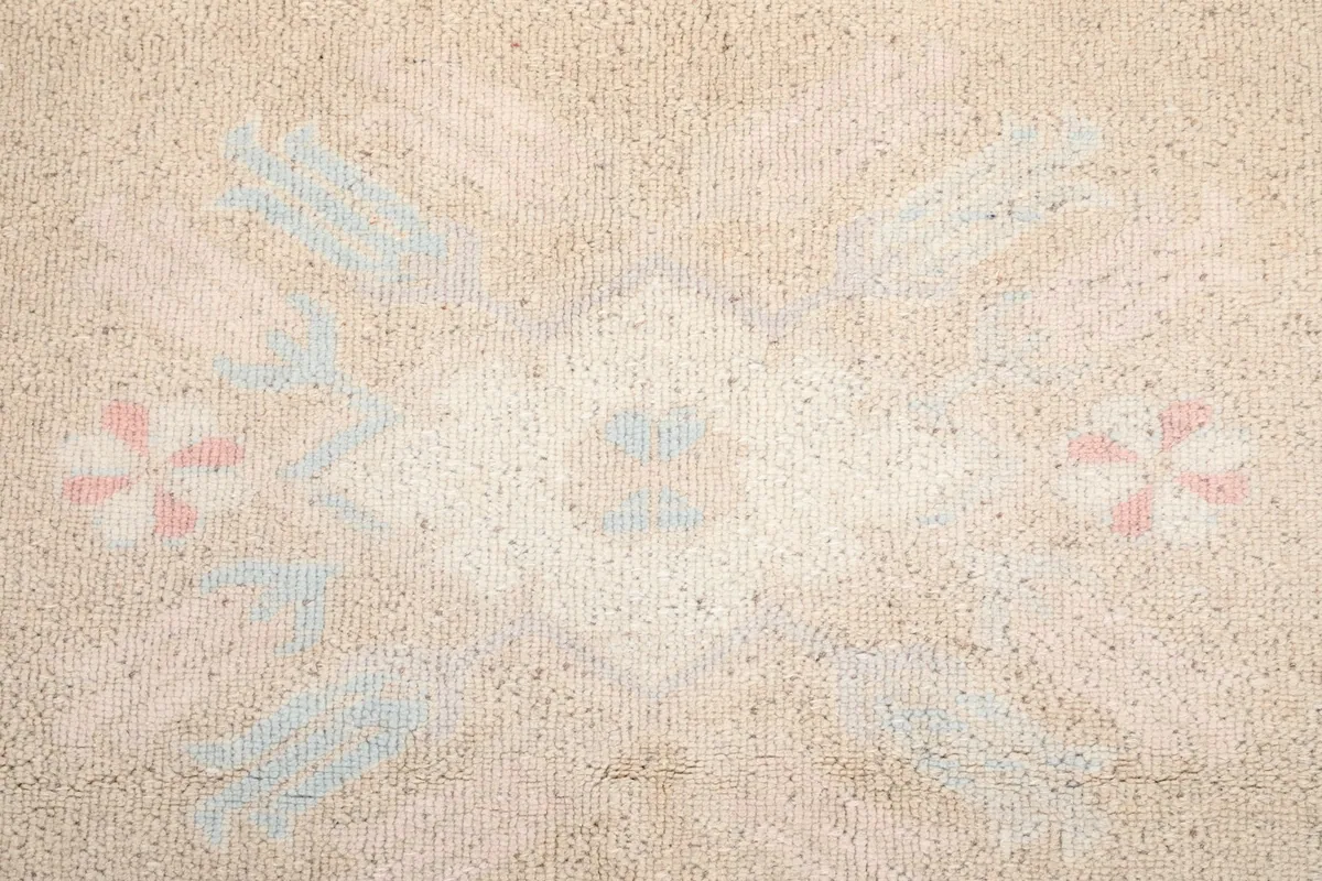 Close-up of the central medallion motif in beige, blue, and rose