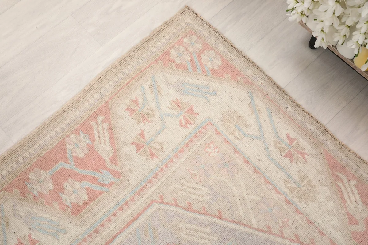 Corner detail of the rug's border with floral and geometric elements in rose