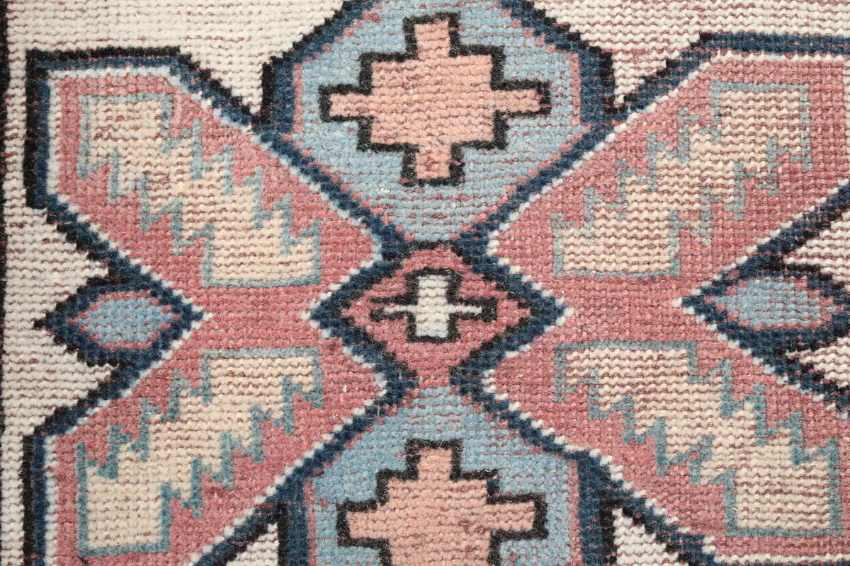 Extreme close-up of a central geometric motif, showing the intricate hand-knotting and color variations.