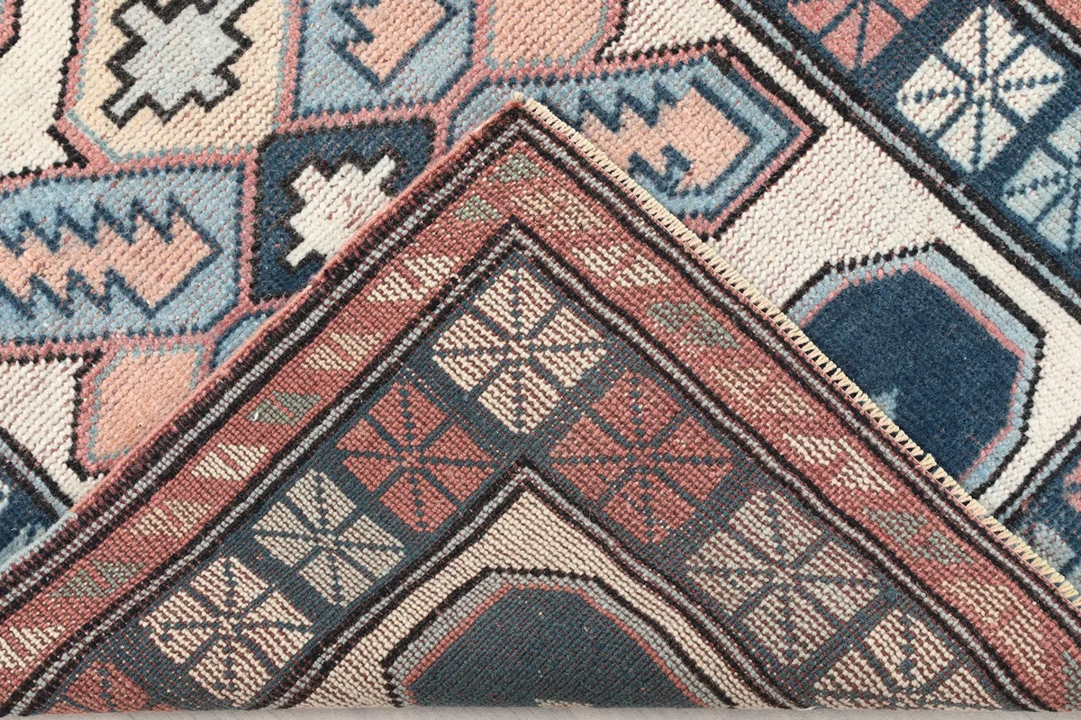 View of the rug folded back to show the reverse side and the hand-knotted wool pile on cotton foundation.