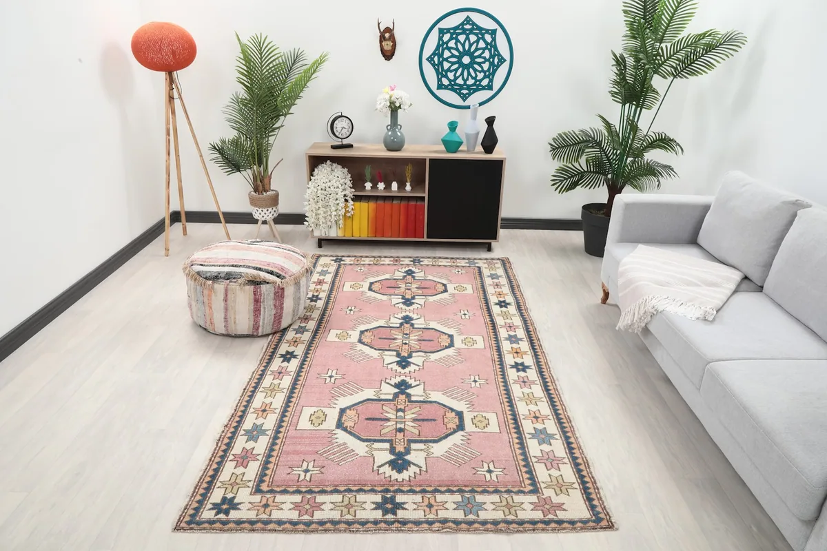 Vintage Anatolian rug with rose field and tribal motifs placed in a modern living room setting.