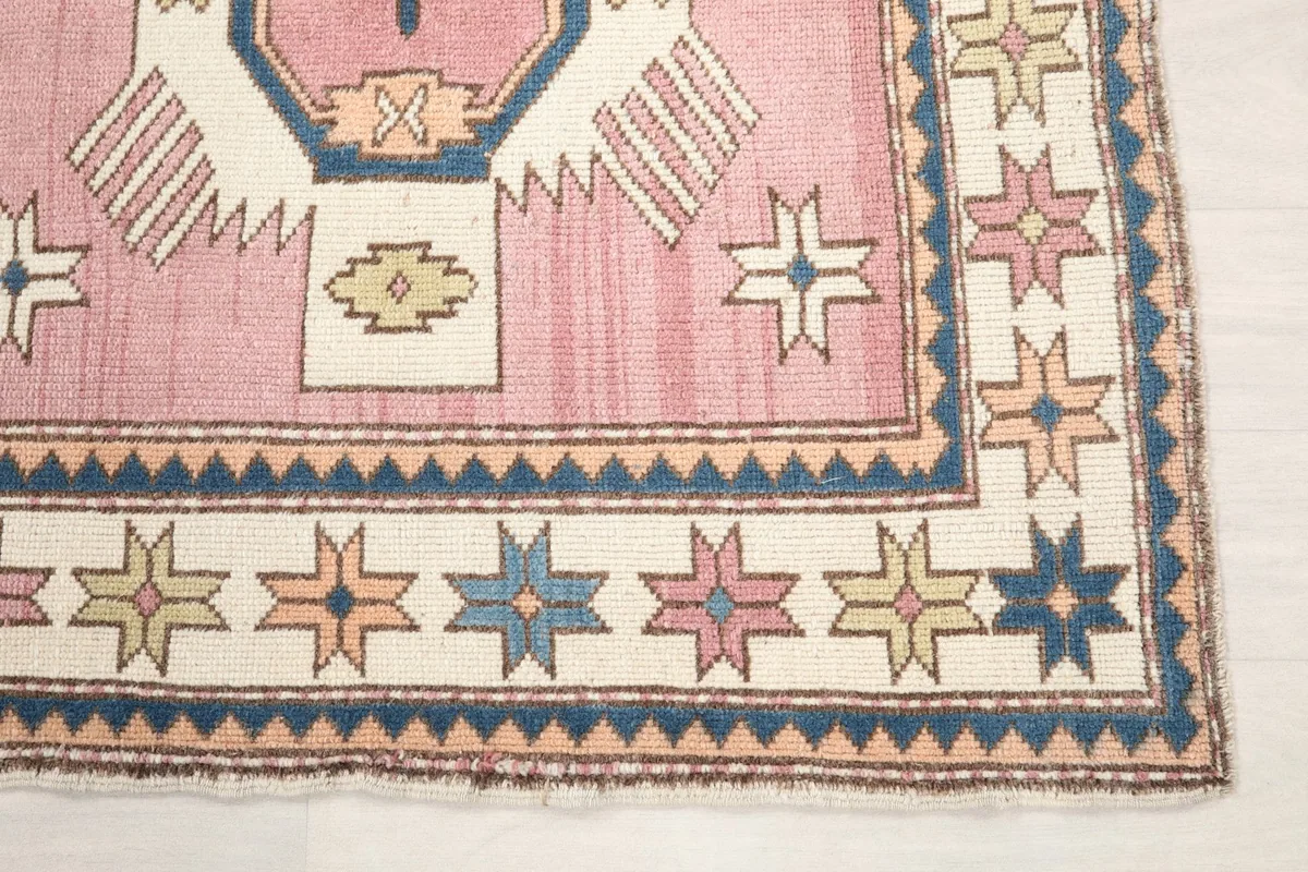 Detail view of the rug's corner with star motifs in the border and part of the main field.