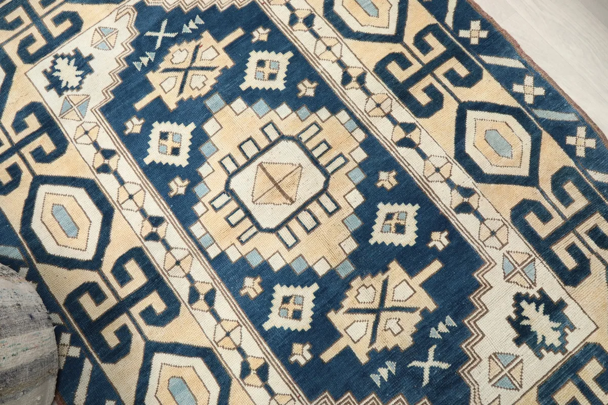 Close-up angle shot of the rug's central medallion and surrounding tribal motifs in navy and beige.