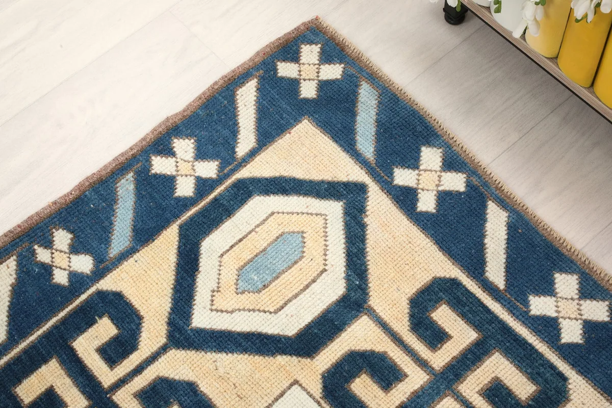 Close-up of a corner of the rug, showing the navy border with light blue and beige details.