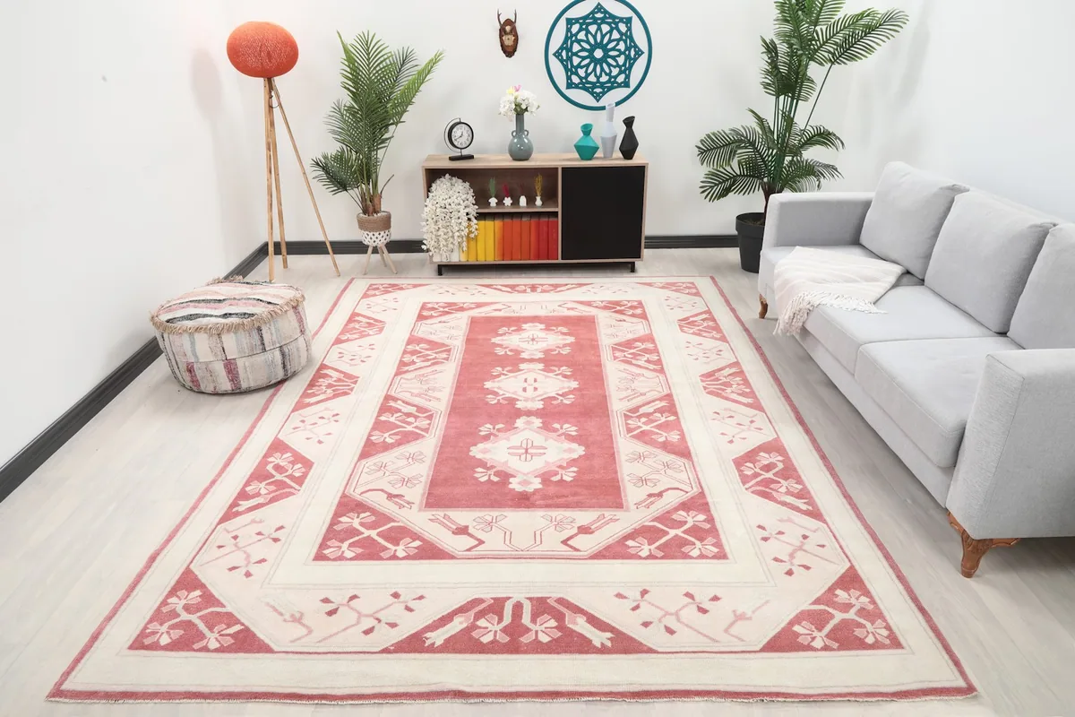 Vintage rose and ivory rug displayed in a bright living room setup with a gray sofa
