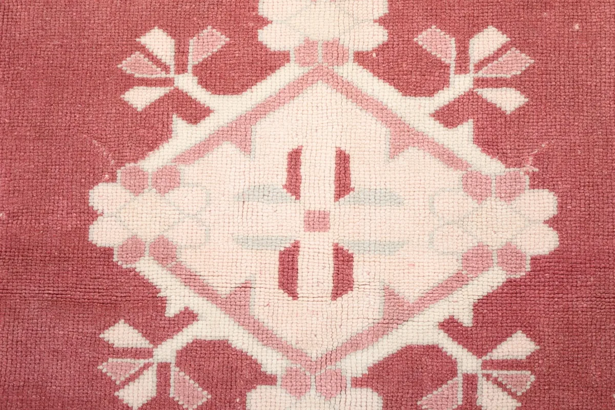 Macro detail of a central ivory geometric medallion with rose accents on the rose field