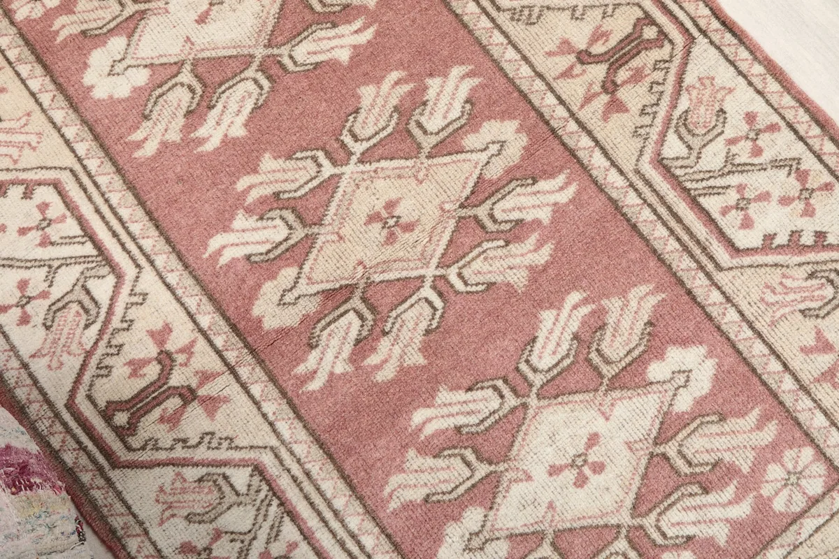 Angled close-up of the central rose field and stylized floral motifs on the vintage rug