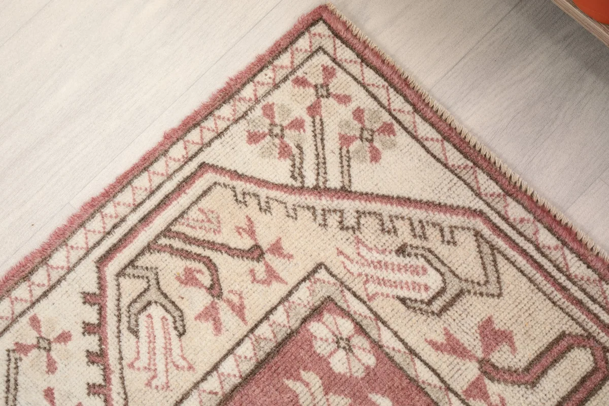 Detailed corner view showing the intricate geometric border and edge of the vintage rug