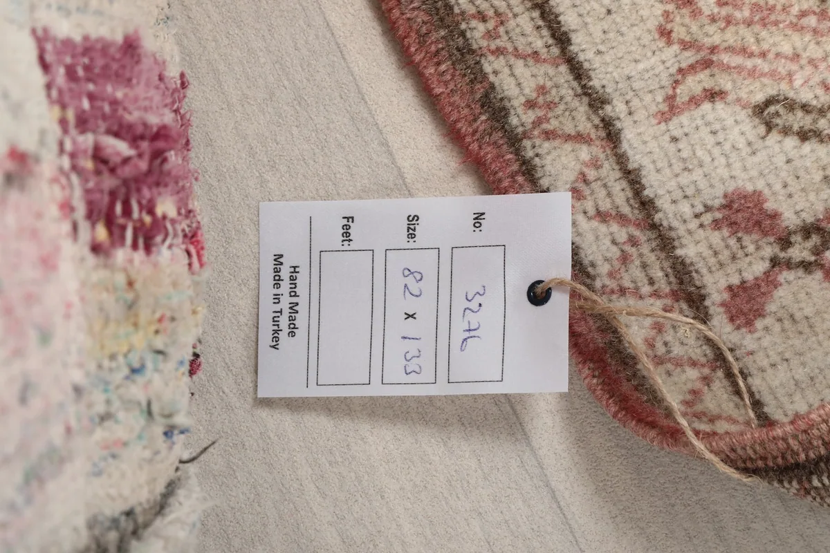 Product tag displaying the rug's dimensions in centimeters and feet, confirming it is handmade in Turkey