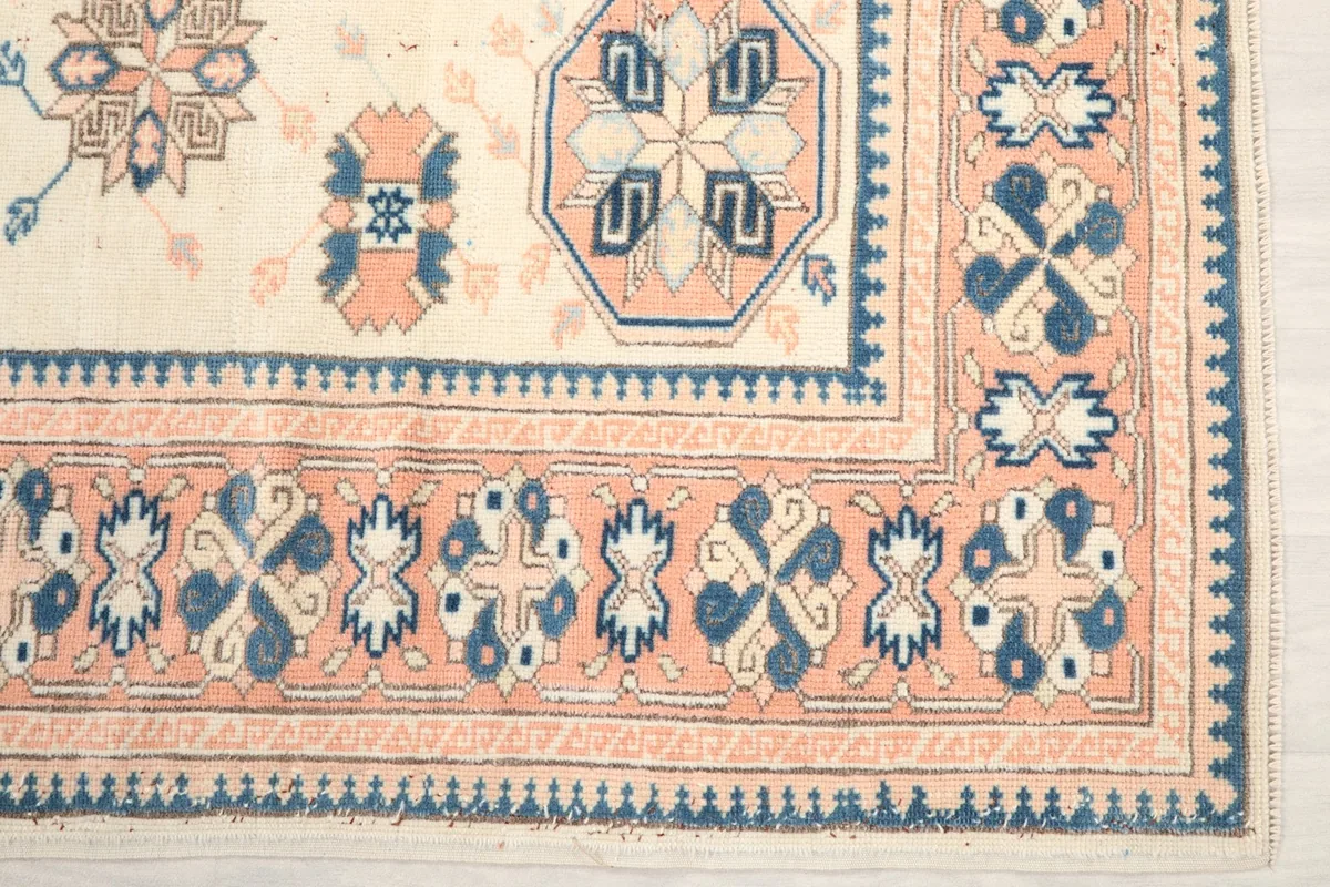 Detail of the rug's border showing rose and navy geometric motifs and corner design
