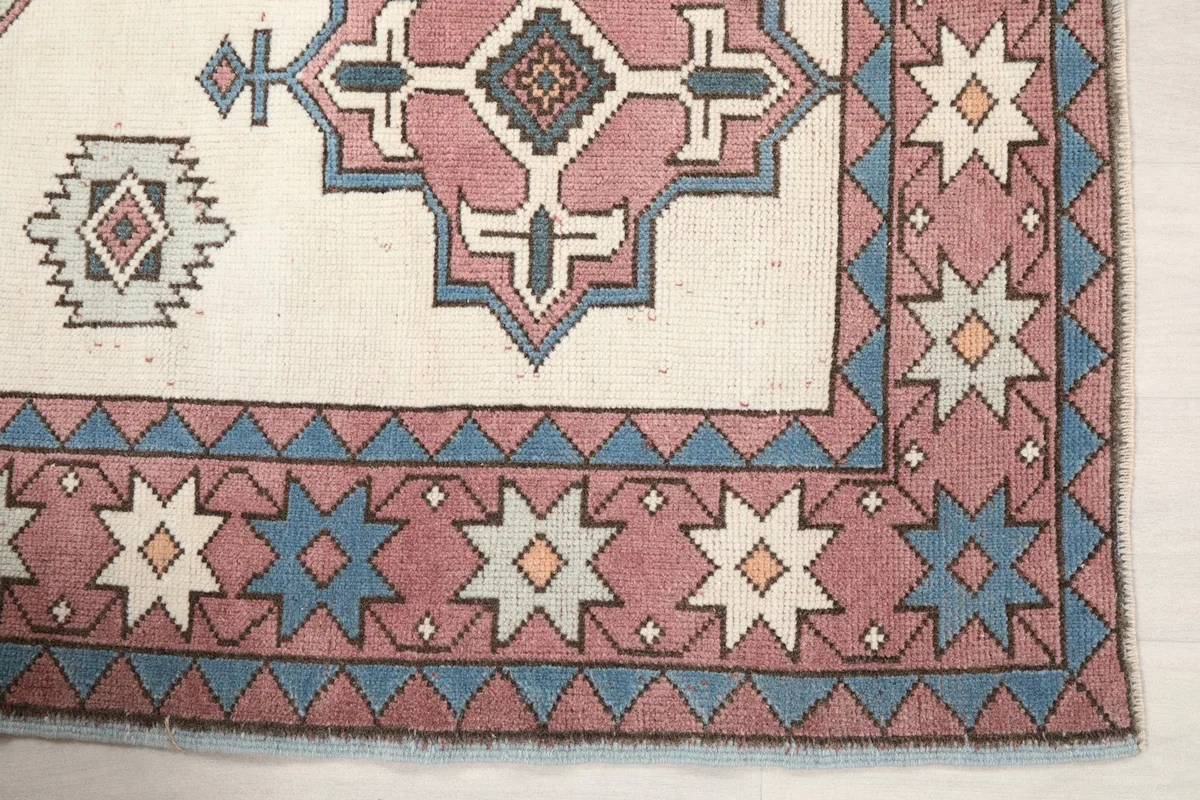 Close-up of the rug's corner, showing the rose border with blue and cream star motifs