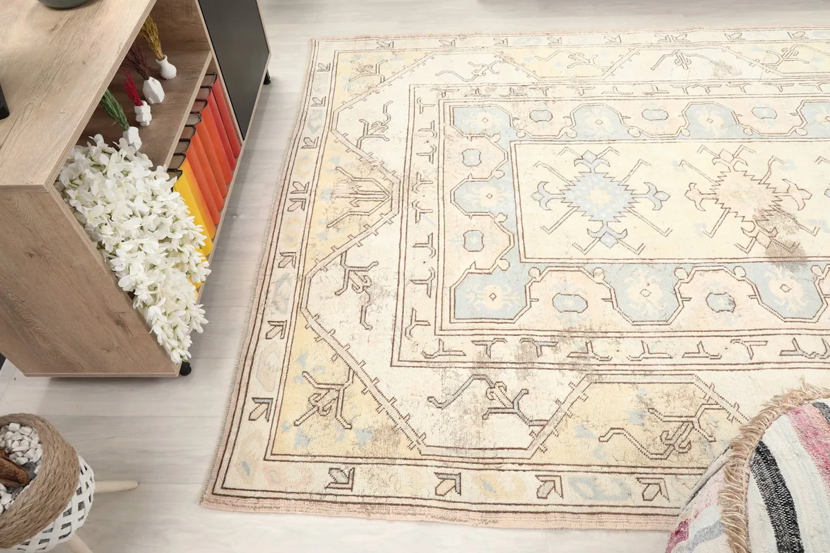 Side angle of the rug in a room, emphasizing its texture and the interplay of cream, blue, and faded tones.