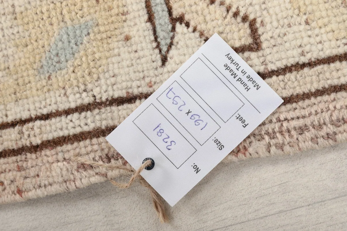Close-up of the rug's edge with a product tag showing the size 199 x 297 cm and its hand-made origin.