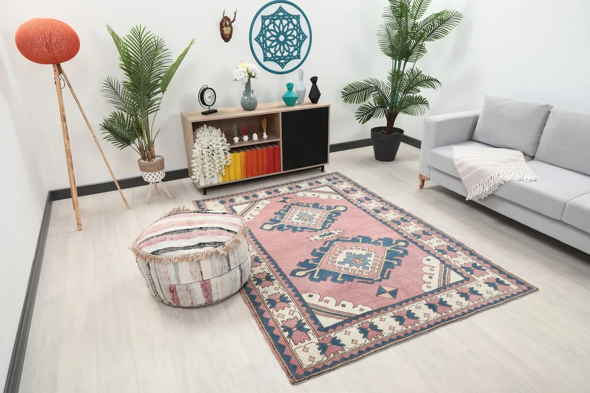 Angle view of the rose and navy Anatolian rug in a living room, showing its placement relative to furniture.
