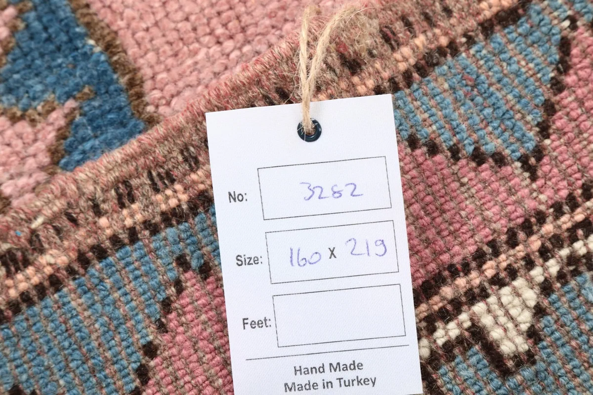 Product tag on the rug, displaying the item number and size in centimeters, indicating hand-made in Turkey.