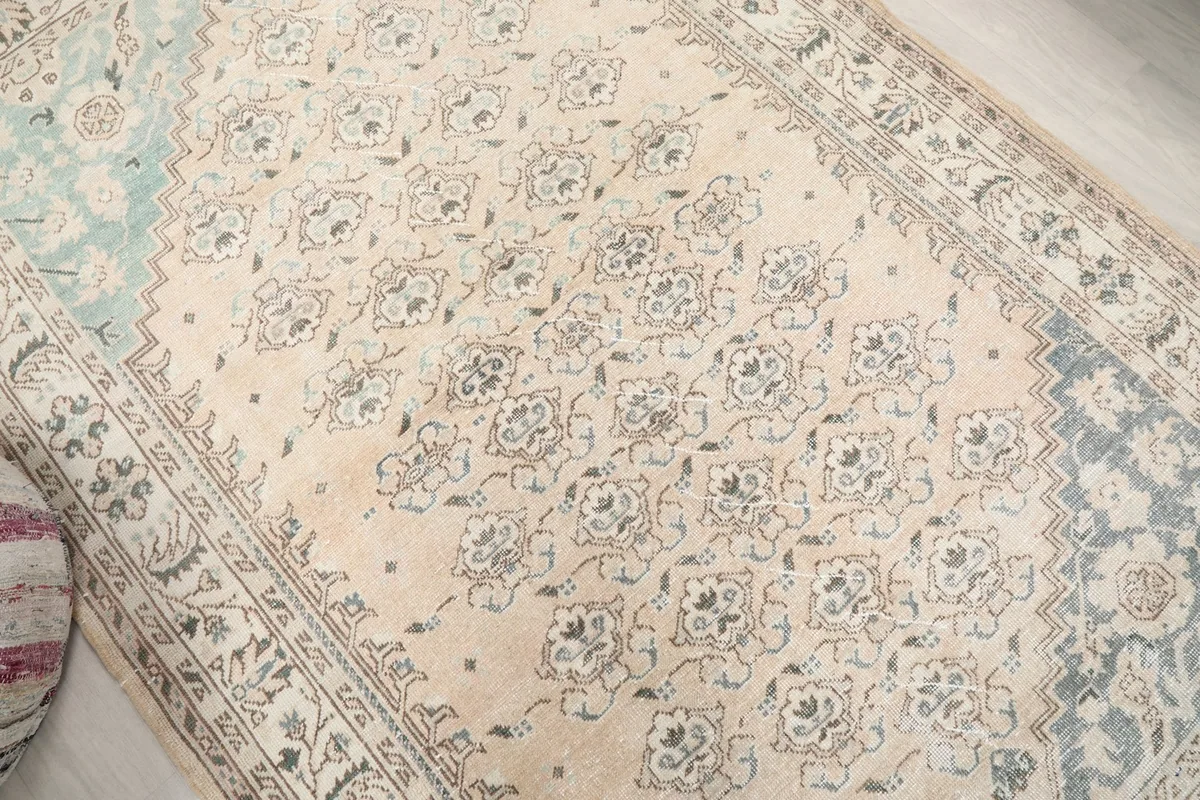 Overhead view showing the repeating floral motifs across the beige field of the rug