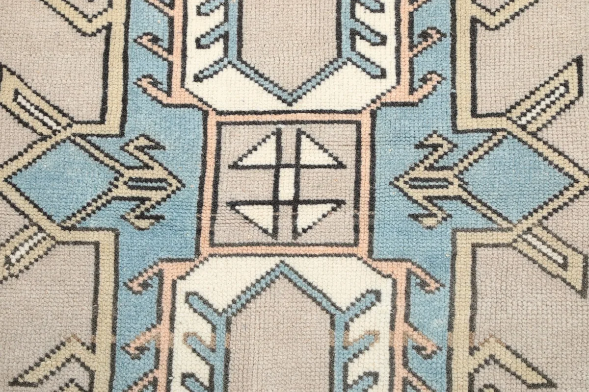 Close-up of the central geometric design within the rug, with blue, gray, and ivory tones