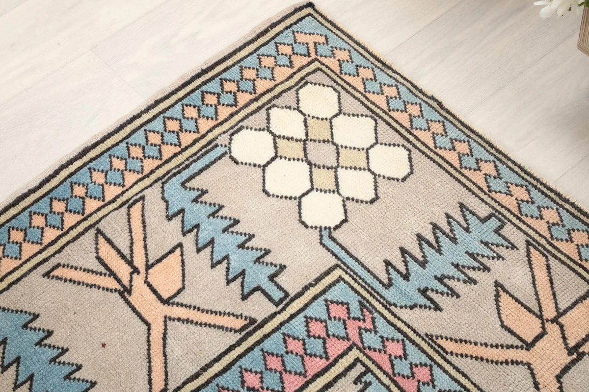 Corner detail of the rug, showing intricate tribal patterns and a blend of blue, pink, and orange