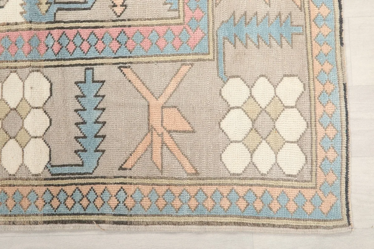 Detail of the rug's outer border, showing blue, orange, and pink patterns against a gray background