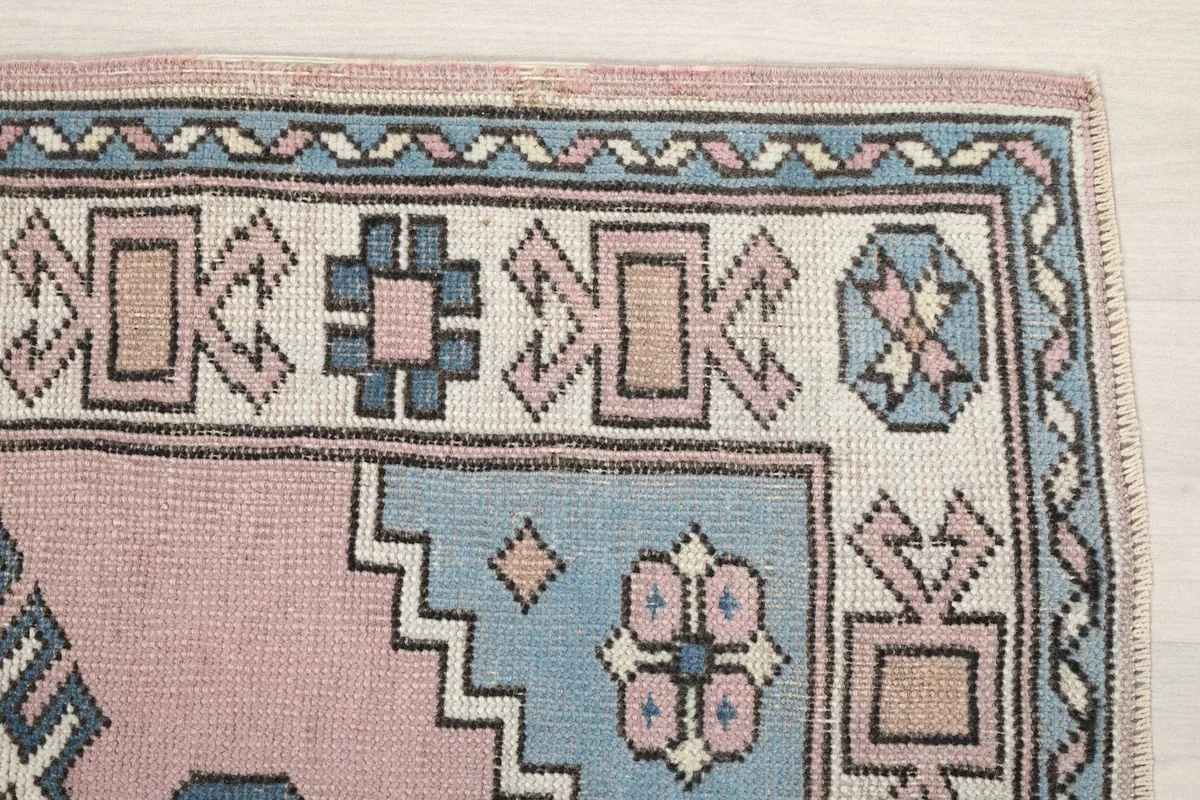 Detailed view of the upper right corner of the rug, showing geometric motifs and border