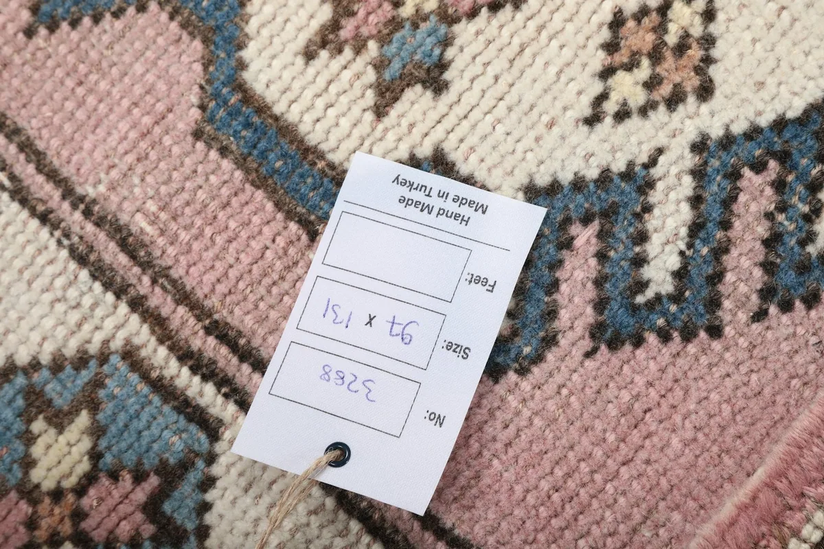 Close-up of the rug's back with a size tag, showing hand-knotted construction