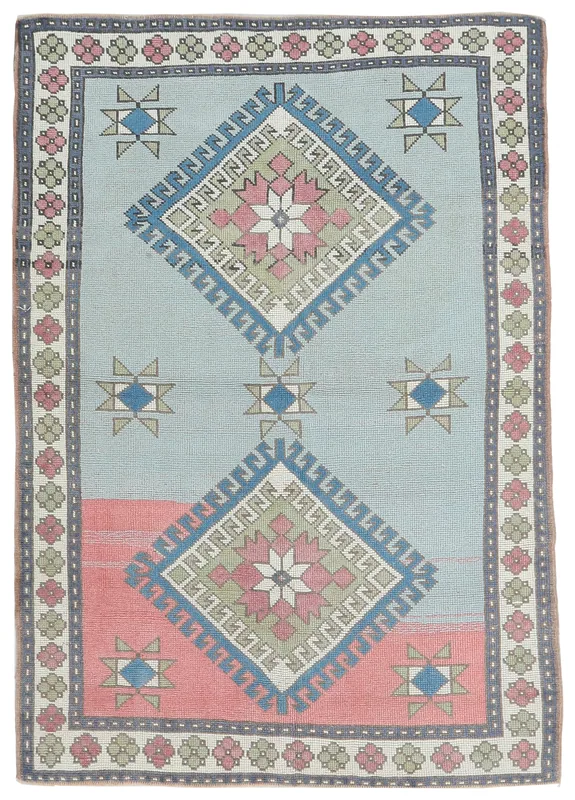 Full overhead view of the blue and rose geometric Anatolian rug on a white background