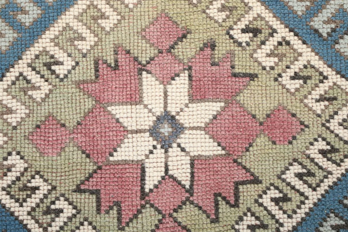 Close-up of the central star-like geometric motif with rose, green, and ivory colors