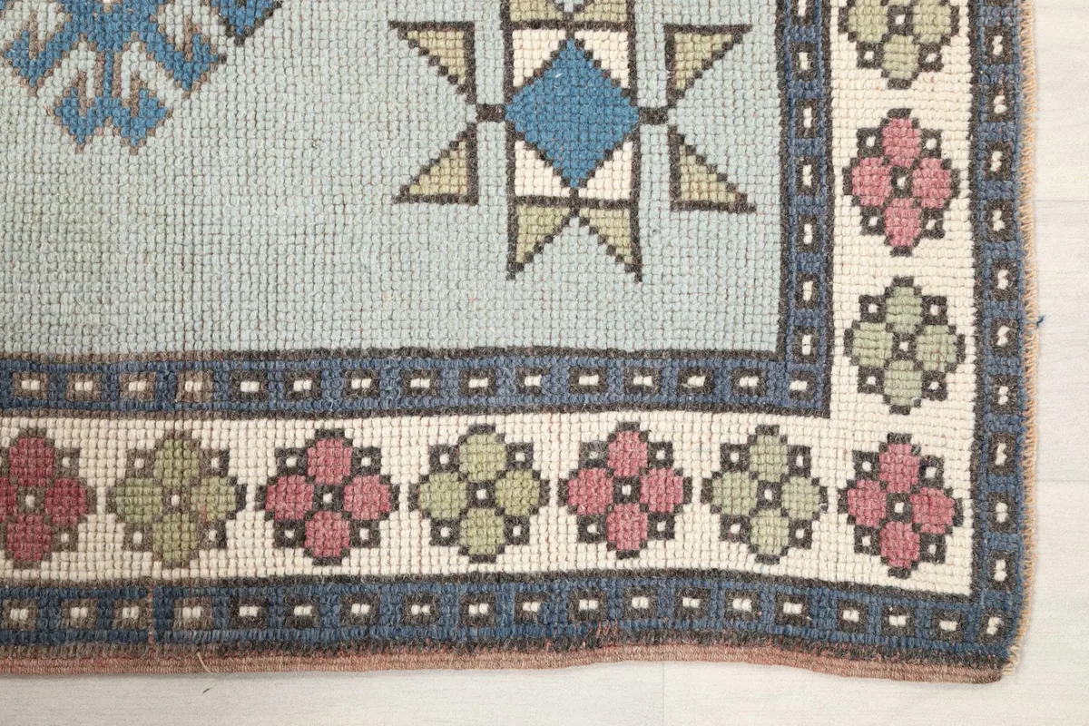 Detail of the border design with ivory, rose, and green floral motifs on the rug