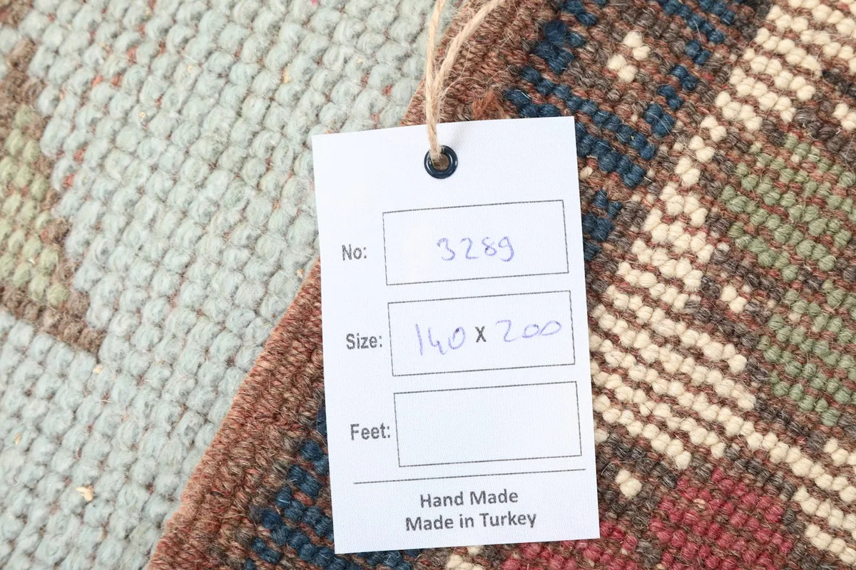Close-up of the product tag indicating the rug's size of 140 x 200 cm and handmade origin