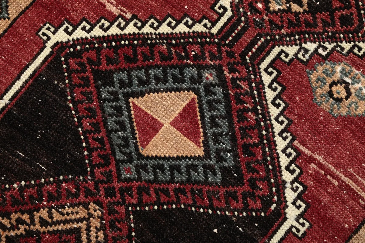 Intricate detail of a square geometric motif with red, tan, and blue accents