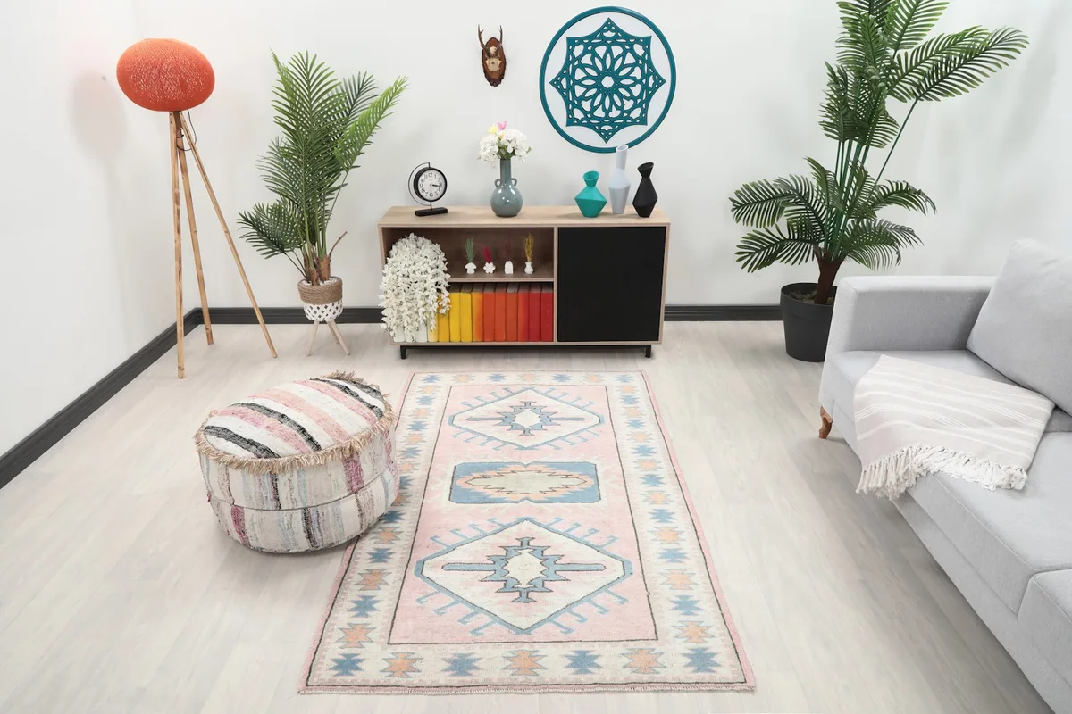 Vintage Anatolian rug displayed in a bright living room setup with a gray couch and wooden cabinet.