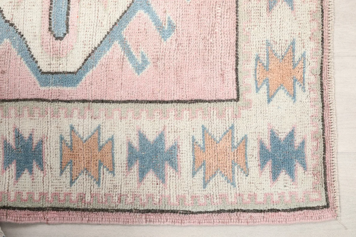 Detailed view of the cream border with blue and orange tribal motifs.