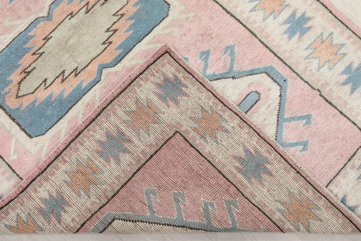 Folded corner of the rug revealing the wool pile and cotton foundation.