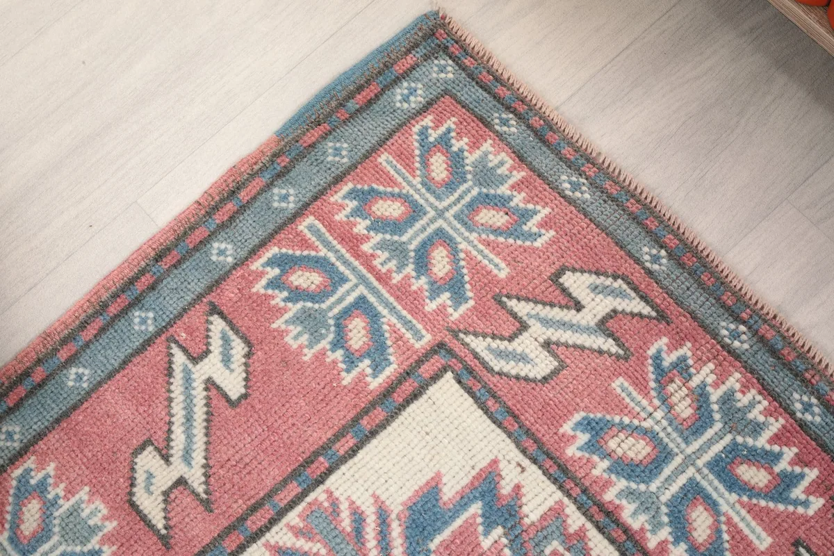 Corner detail of the rug, highlighting the intricate blue and rose tribal patterns and border.