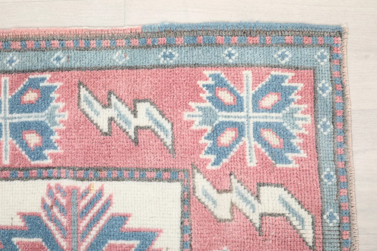 Detail of the blue border and corner of the rug, showing the hand-knotted wool pile and design.