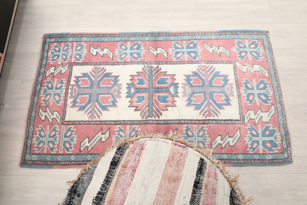Full overhead view of the rug, showing its rectangular shape and overall pattern, with a pouf in foreground.