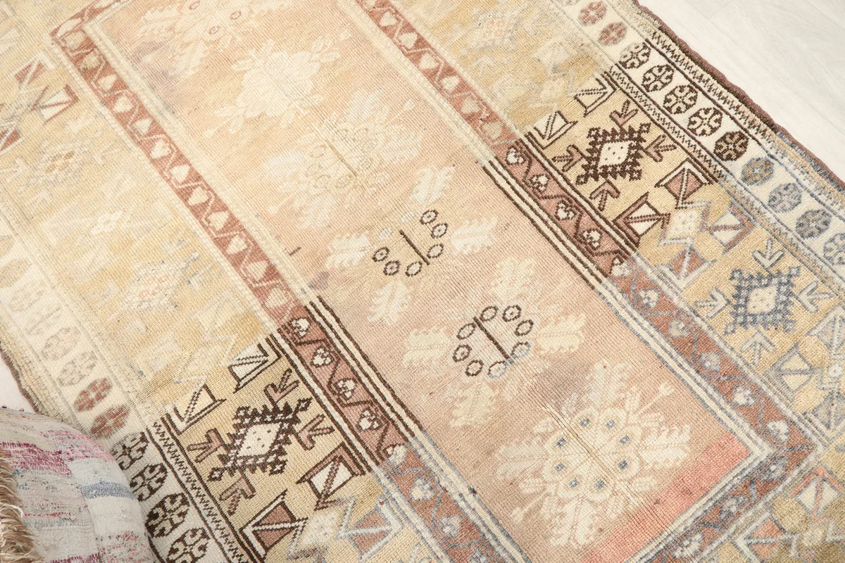 Angled close-up of the Faded Rose Tribal Anatolian Rug's faded rose center and surrounding tribal designs.