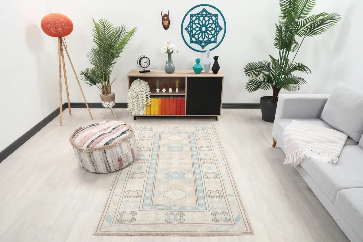Beige and blue vintage Anatolian rug in a room setting, showing its scale with furniture.