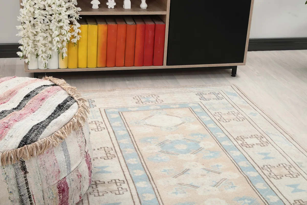 Close-up of the rug's central beige field and blue geometric border in a room.