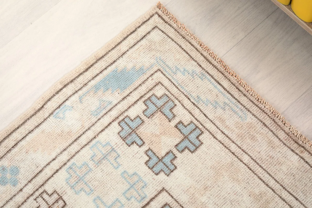 Corner detail of the rug, showing the blend of beige, blue, and charcoal colors.