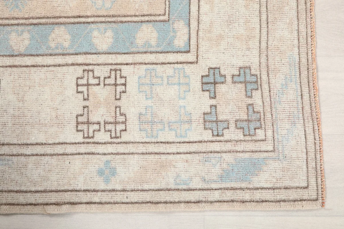 Detail of the outer border with charcoal and blue geometric cross motifs.