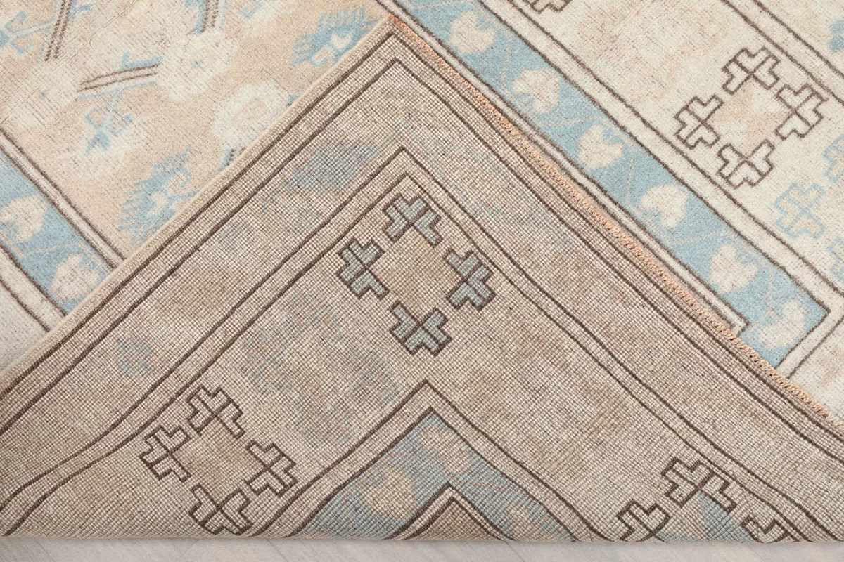Folded corner of the rug, showing the back of the hand-knotted cotton foundation.