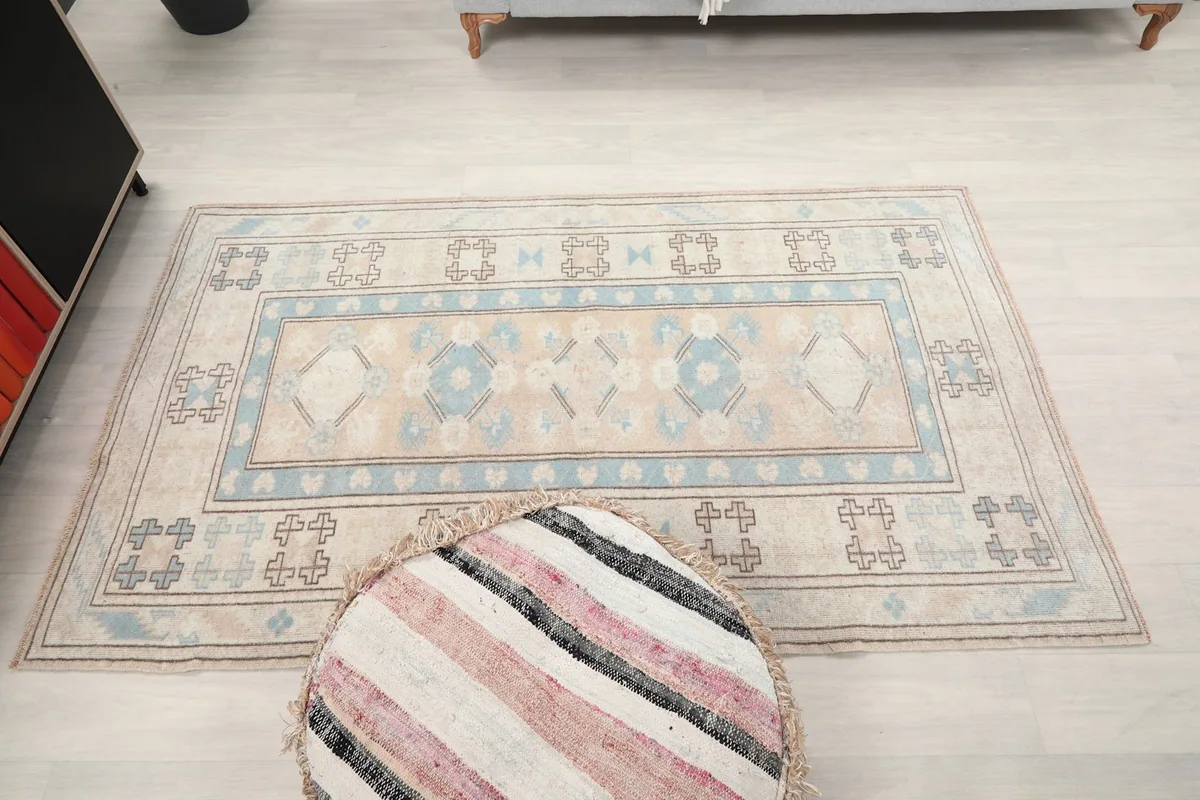 Full overhead view of the beige and blue rug's entire surface in a room setting.